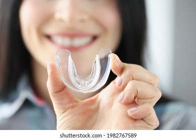 Smiling Woman Holds Transparent Plastic Mouth Guard In Her Hand