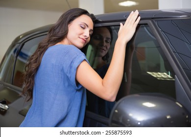 Smiling Woman Hugging A Black Car At New Car Showroom