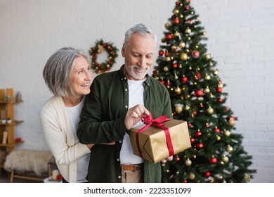 smiling woman hugging mature bearded husband with christmas present - Powered by Shutterstock