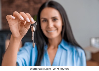 Smiling woman with keys from her new house in living room, focus on keys. Crop close up of female tenant renter show praise house keys moving to first own apartment. Relocate, rental, rent concept