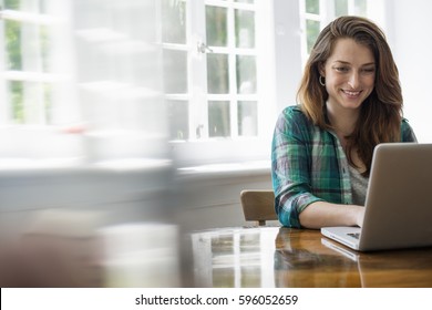 Smiling woman with laptop in home office - Shutterstock ID 596052659