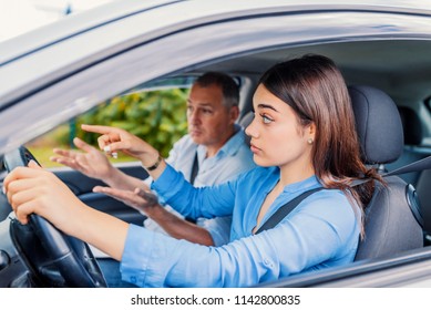 Smiling Woman Learns To Drive In Car With Instructor. Learning To Drive . Student Driver Taking Driving Test. Woman Taking Driving Lessons From Instructor