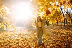 
Smiling Woman In A Light Coat With A Retro Camera Spends Time Having Fun In The Autumn Forest. Happy Mood, Leisure Time. Lifestyle Concept.