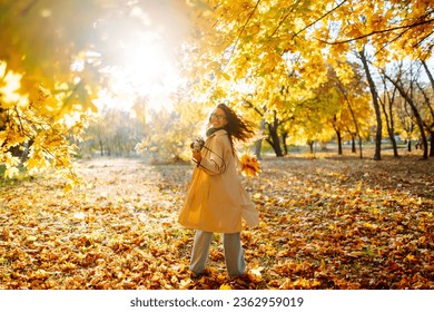 
Smiling woman in a light coat with a retro camera spends time having fun in the autumn forest. Happy mood, leisure time. Lifestyle concept. - Powered by Shutterstock