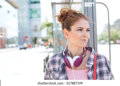 Lächelnde Frau, die wegschaut, während sie an der Bushaltestelle wartet