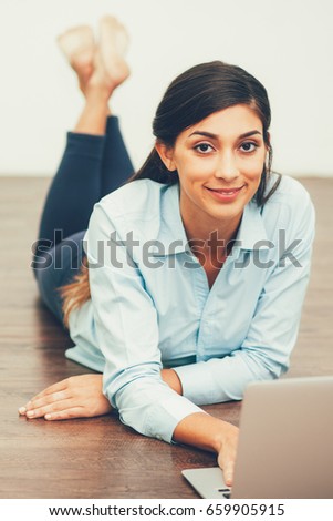 Smiling Woman Lying on Floor and Working on Laptop