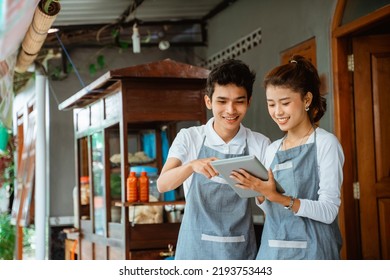 smiling woman and man merchant using digital tablet at chicken noodle cart stall - Powered by Shutterstock