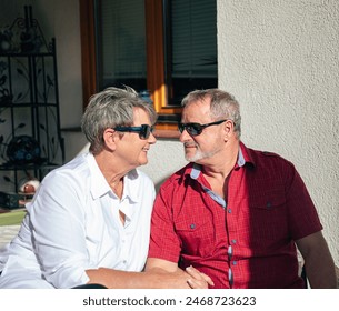 Smiling woman and man in sunglasses looking at each other with fondness on their porch - Powered by Shutterstock