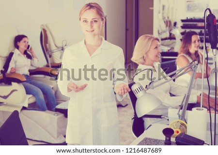 Smiling woman manicurist demonstrating her workplace in nail salon
