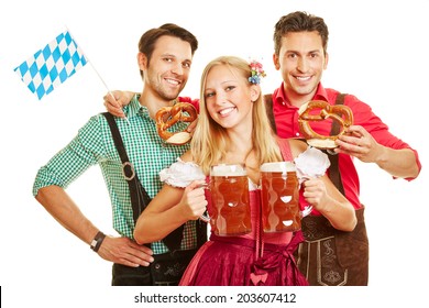 Smiling woman at Oktoberfest carrying two beer glasses in front of two men