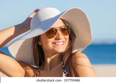 smiling woman on vacation with  sun hat and glasses. 