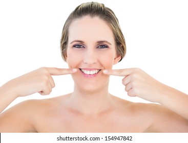 Lächelnde Frau auf weißem Hintergrund, die auf eine Falte an ihren Mundecken zeigt
