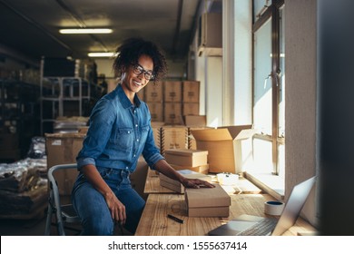 Smiling woman packing the parcel for shipping to the customer. Online business owner working at the office, preparing the order. - Shutterstock ID 1555637414