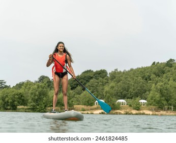 Smiling woman paddleboarding on lake - Powered by Shutterstock