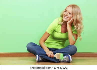 Smiling Woman With Painting Brush Sitting Near The Wall