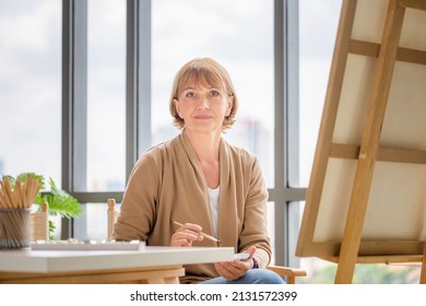 Smiling Woman Painting On A Canvas, Mature Middle Aged Woman Painting On Canvas At Home, Happy Retirement Concepts