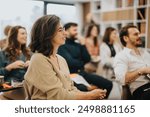 Smiling woman participating in a professional workshop with colleagues in a modern office setting, conveying engagement and teamwork.