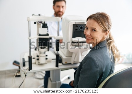 Smiling woman patient awaits a vision test at opticians shop or ophthalmology clinic