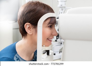 Smiling Woman Patient Having a refractor Exam / eye Doctor is doing a Eyeglass prescription a patient during an refraction test /optometrist in eyes clinic is checking the retinoscopy diagnostic