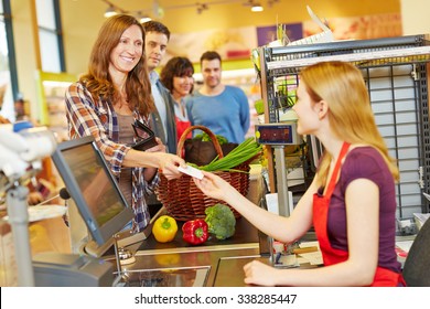Smiling woman paying with her EC card at supermarket checkout