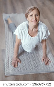 Smiling Woman Performs Yoga. Standing In Upward-Facing Dog Pose. Happy Mature Woman Does Exercises For Flexible Spine. Top View. Facing.