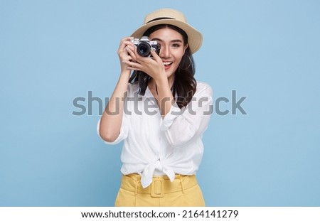 smiling Woman photographer is taking images photo with dslr camera isolated studio blue background.