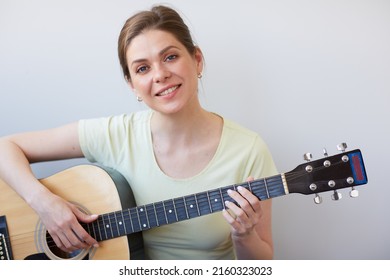 Smiling Woman Play On Guitar. Isolated Portrait On Gray Back.