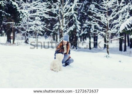 smiling woman playing with dog in snowy weather