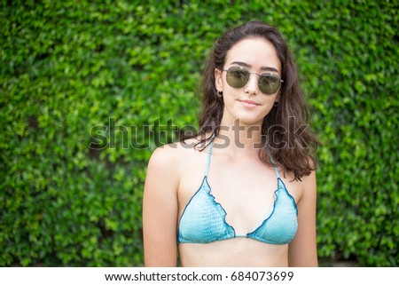 Smiling woman posing in sunglasses and bikini