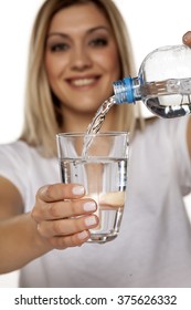 Smiling Woman Pouring Water From A Plastic Bottle Into A Glass