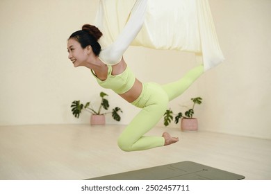 Smiling Woman Practicing Aerial Yoga on Hammock - Powered by Shutterstock