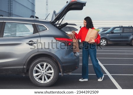 smiling woman put bags in car trunk