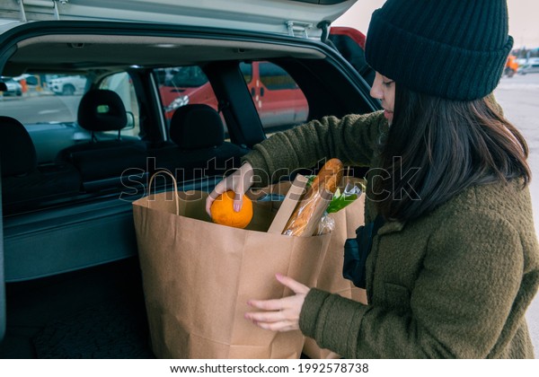 smiling woman put bags with products in car trunk\
after grocery store copy\
space