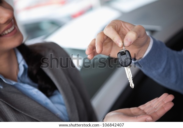 Smiling\
woman receiving keys from someone in a car\
shop