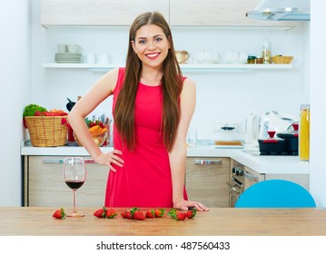 Smiling Woman In Red Dress Standing In Kitchen.