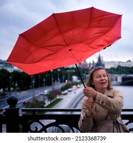 Smiling Woman With Red Umbrella During Strong Wind And Stormy Weather