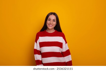 A smiling woman in a red and white striped sweater stands against a bright yellow background. Perfect for themes of fashion, casual style, positivity, and vibrant lifestyle imagery. - Powered by Shutterstock