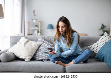 Lächelnde Frau entspannen sich auf Sofa zu Hause halten Handy. Online-Shoping mit Smartphone.