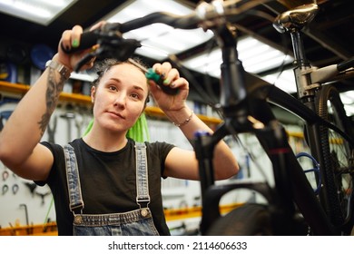 Smiling Woman Repairing Bike In Workshop