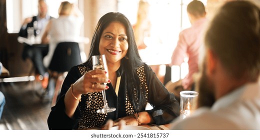 Smiling woman in a restaurant holding a glass, enjoying a meal. The restaurant setting is lively, with people dining and chatting in the background. Diverse couple toasting with champagne. - Powered by Shutterstock