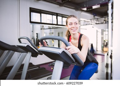 Smiling Woman Riding An Exercise Bike In Gym