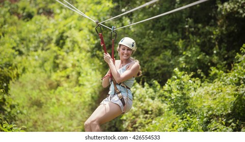 Smiling Woman Riding A Zip Line In A Lush Tropical Forest 