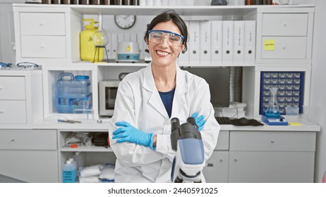 Smiling woman scientist with safety glasses in laboratory surrounded by equipment and chemicals. - Powered by Shutterstock