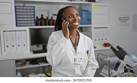 Smiling woman scientist in white lab coat talking on phone in a laboratory with microscope and computer. - Powered by Shutterstock