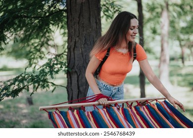 Smiling woman setting up a colorful hammock in a forest, enjoying the outdoors on a bright, sunny day. - Powered by Shutterstock