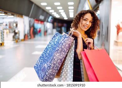 Smiling woman with shopping bags enjoying shopping in the mall.Young woman with packages after shopping. Purchases, black friday, discounts, sale concept.