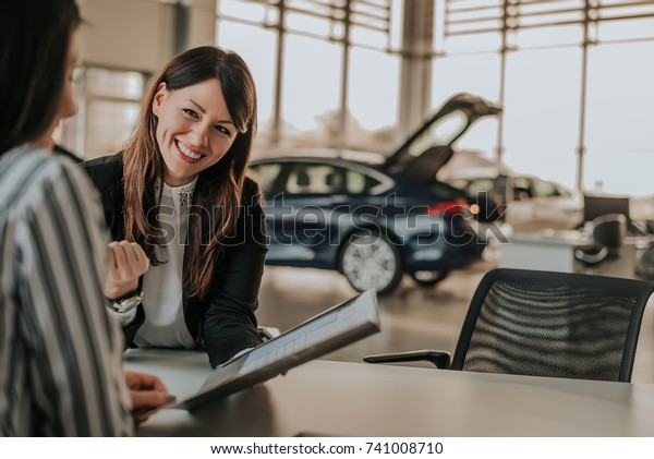 Smiling woman
showing car folder in car
salon.
