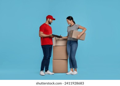 Smiling woman signing order receipt on light blue background. Courier delivery - Powered by Shutterstock