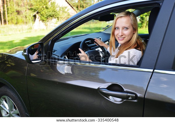 Smiling woman\
sit in car.car stands on green glade\
