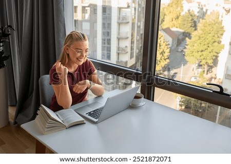 Smiling woman sitting in officeworking using laptop.